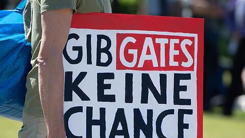 Schild mit der Aufschrift "Gib Gates keine Chance". Foto: Christophe Gateau/dpa/Archivbild