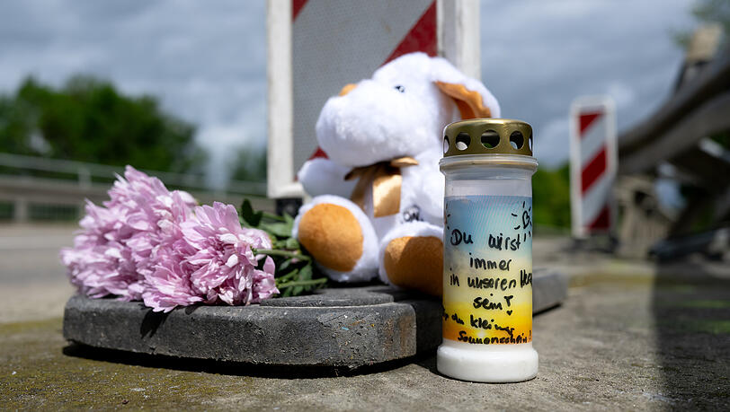 Kerzen, Blumen und ein Stofftier stehen nach dem Busunfall an der Unfallstelle im Landkreis Dachau.