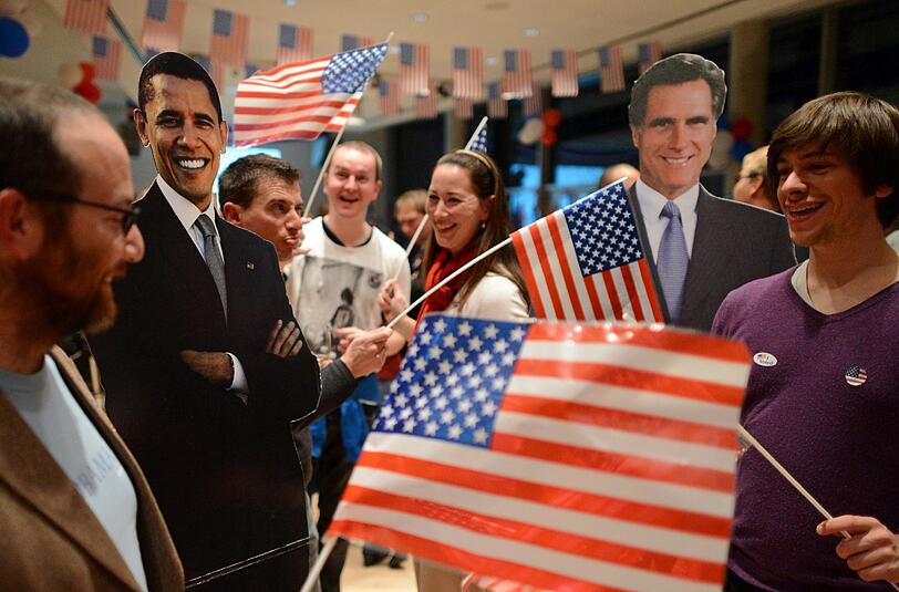 Junge Amerikaner schwenken Fahnen zwischen den Papp-Figuren von US-Präsident Barack Obama und seinem republikanischen Herausforderer Mitt Romney auf einer Wahlparty des US-Generalkonsulates in Leipzig.