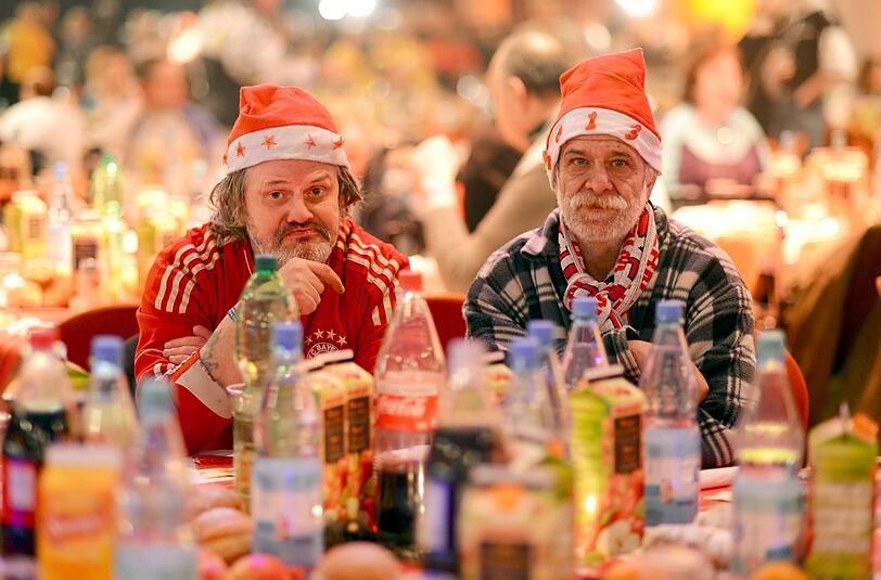 Klaus (l.) und Peter sitzen im beim traditionellen Weihnachtsessen für Obdachlose an einem Tisch.