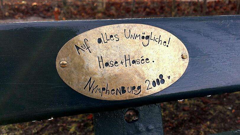 Im Englischen Garten und Nymphenburger Schlosspark haben Münchner tausende Plaketten mit Widmungen auf Parkbänken angebracht.