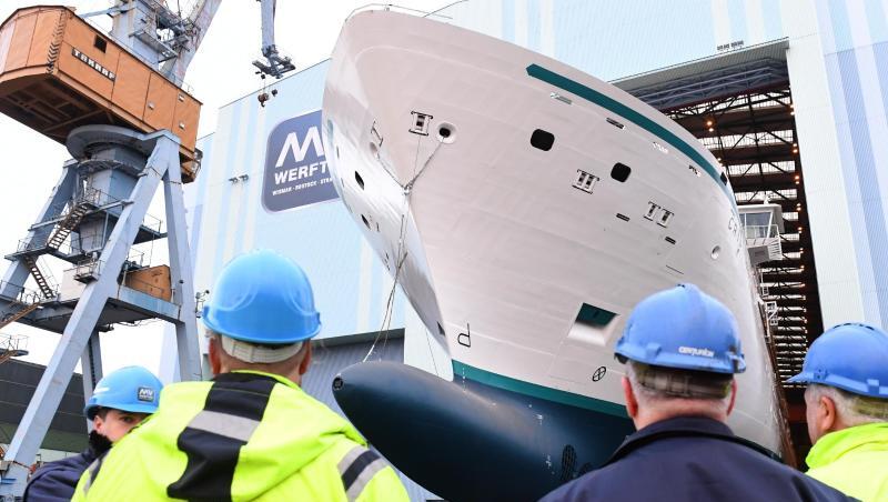 Mitarbeiter beobachten, wie ein Neubau auf der Stralsunder MV Werft eine Schiffbauhalle verlässt. Mitarbeiter beobachten, wie ein Neubau auf der Stralsunder MV Werft eine Schiffbauhalle verlässt.