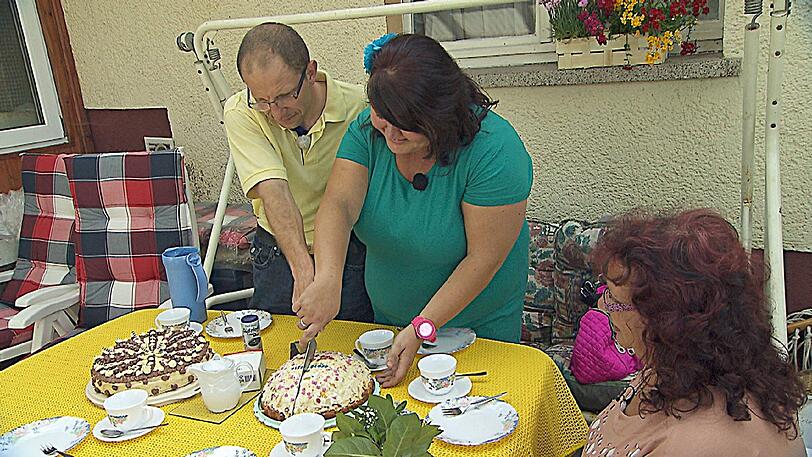 Steffen und Nicole (Mi.) schneiden die 'Verkuppeltorte' an, die Steffens Mutter zur Begrüßung von Nicole gebacken hat.