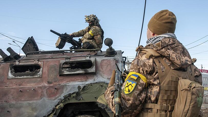 Ukrainische Soldaten inspizieren ein beschädigtes Militärfahrzeug nach Kämpfen in Charkiw.