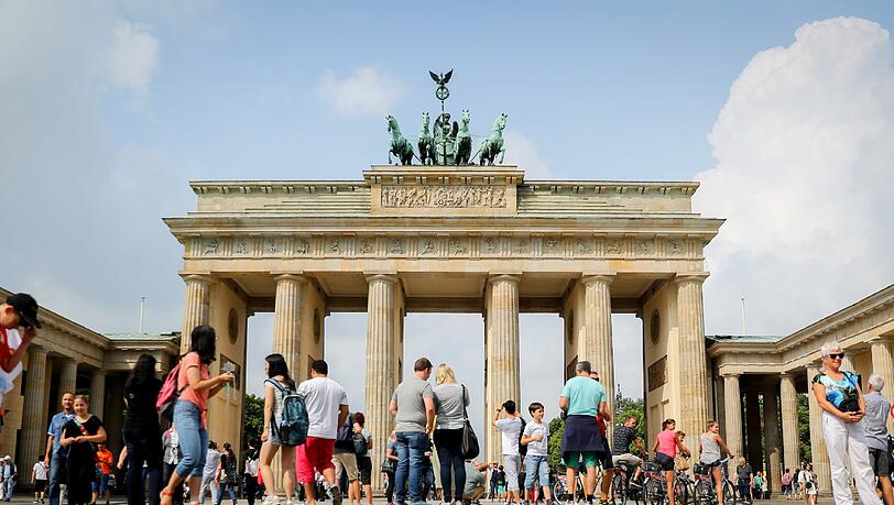 Touristen stehen in Berlin vor dem Brandenburger Tor. Foto: Kay Nietfeld Touristen stehen in Berlin vor dem Brandenburger Tor. Foto: Kay Nietfeld