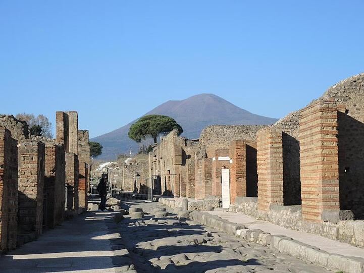 Eine Straße im Archäologischen Park Pompeji mit Blick auf den Vesuv.