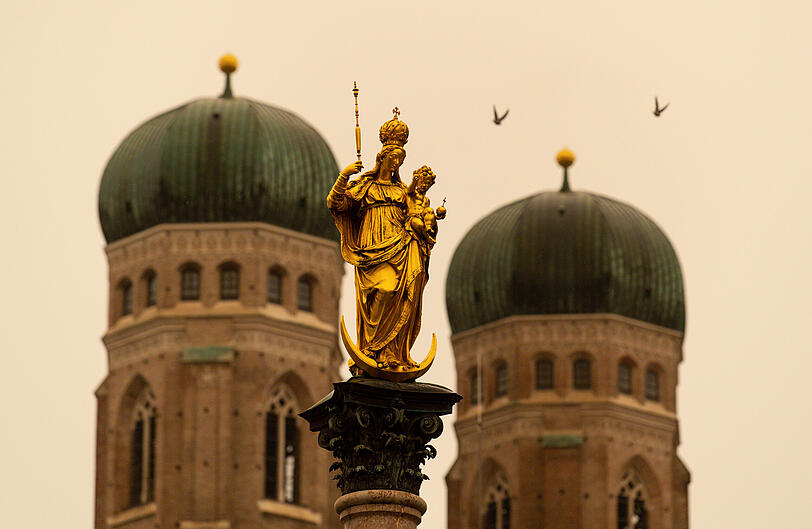 Blick auf die Mariensäule: Orange-roter Himmel, "Blutregen" und Saharastaub: Ein Wetterphänomen hat den Himmel über München komplett verfärbt.
