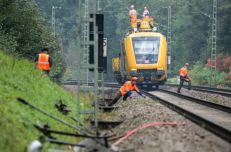 Arbeiter der Bahn reparieren die Oberleitung.
