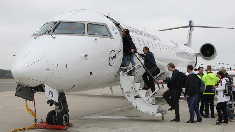 Passagiere gehen auf dem Flughafen zur Lufthansa-Maschine vom Typ CRJ900. Foto: Bernd Wüstneck