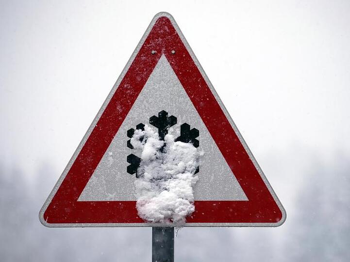 Ein Verkehrsschild ist mit Schnee bedeckt. Foto: Karl-Josef Hildenbrand