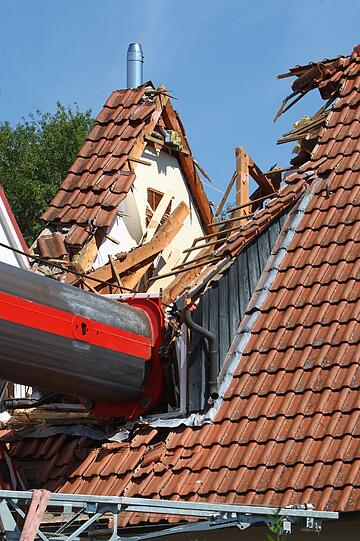 Eine Aktion, die schief ging: Als Bauarbeiter einen Kran über einen Mauer heben wollten, kippte das Fahrzeug um.