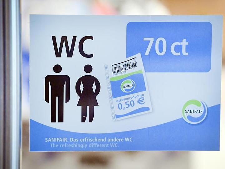 In der Tür einer Tank- und Rastanlage hängt ein Schild mit dem Schriftzug "Sanifair". Foto: Stefan Sauer/Archivbild