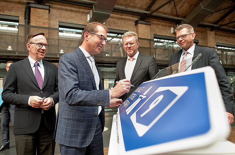 Bundesverkehrsminister Alexander Dobrindt (zweiter v.l. )unterschreibt symbolisch auf einem Autobahnschild der A9.