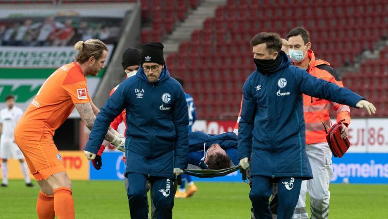Schalkes Torwart Ralf Fährmann (l) beugt sich zu Mark Uth, der auf einer Trage verletzt vom Spielfeld getragen wird.
