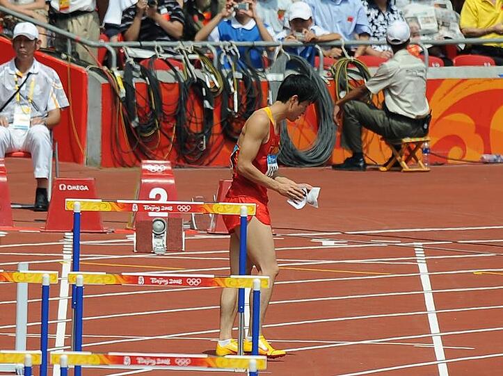 Enttäuscht reißt sich Liu Xiang die Startnummern ab und verlässt das Stadion.