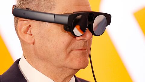 Bundeskanzler Olaf Scholz mit eier AR-Datenbrille (Augmented Reality) zur Prozessüberwachung einer Maschine.