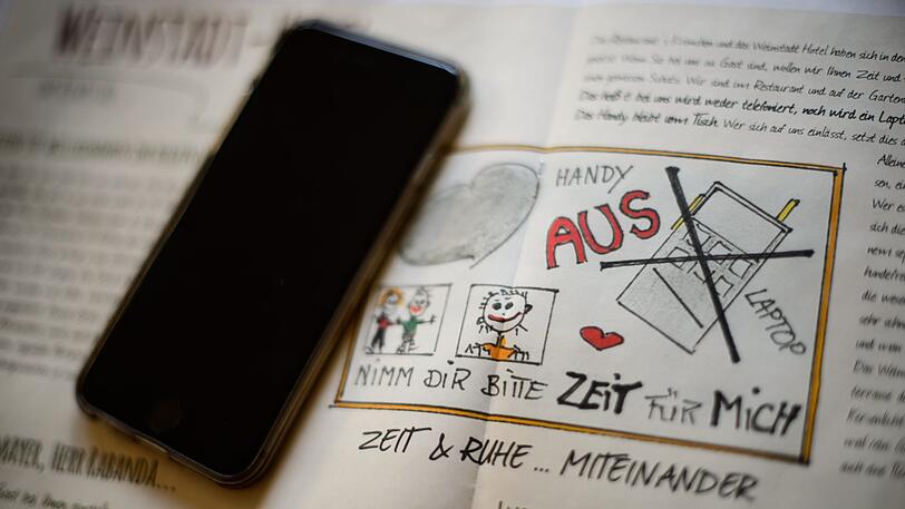 Ein Handy liegt auf einer Broschüre mit der Aufforderung "Handy aus". Im Weinstadt- Hotel sind Handys und Laptops verboten - zumindest im Frühstückssaal, auf der Sonnenterrasse und im angrenzenden Restaurant.