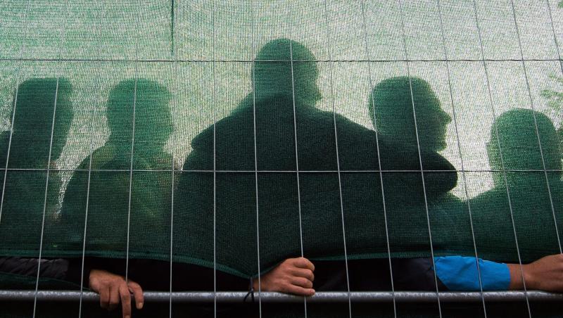 Flüchtlinge stehen im Spätsommer 2015 in einer Flüchtlingsunterkunft in Hamburg hinter einem Zaun. Flüchtlinge stehen im Spätsommer 2015 in einer Flüchtlingsunterkunft in Hamburg hinter einem Zaun.