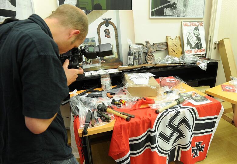 Bei der Razzia beschlagnahmte Gegenstände: Darunter sind ein Karabiner, ein Metzgerbeil, Bajonette und  Hakenkreuzfahnen.