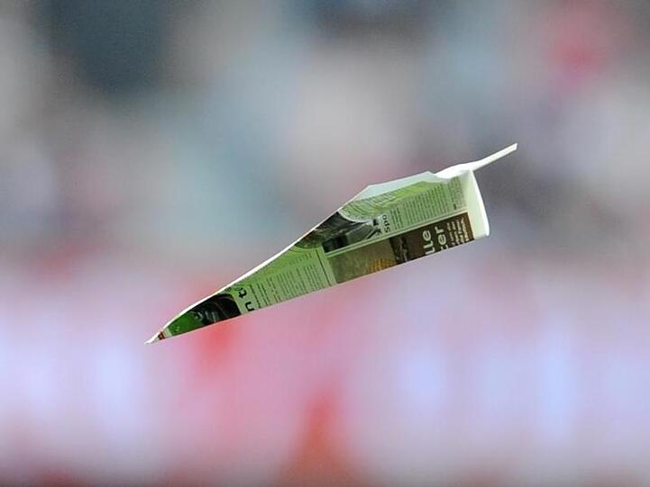 Ein Papierflieger im Flug beim Audi-Cup in der Allianz Arena in München. Foto: Tobias Hase/Archiv