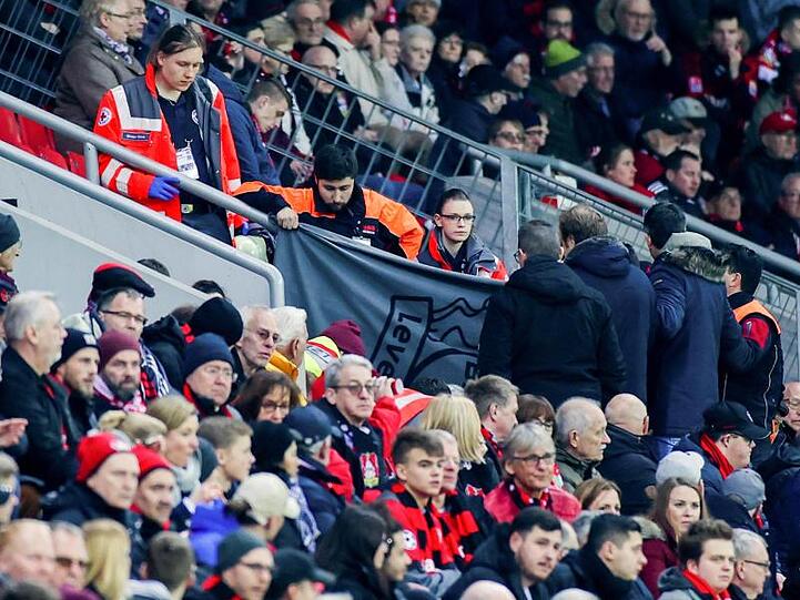 Sanitäter kümmern sich in der BayArena um eine Person auf der Tribüne.