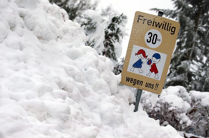 Ein Hinweisschild auf spielende Kinder im Schneehaufen - gesehen im bayerischen Aitrang.