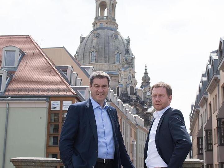 Ministerpräsident Michael Kretschmer (r) und Ministerpräsident Markus Söder stehen vor der Frauenkirche. Foto: Sebastian Kahnert