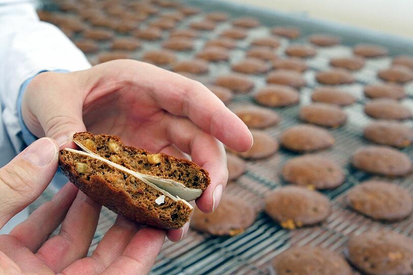 Ein Mitarbeiter der Lebkuchenfabrik Ferdinand Wolff GmbH in Nürnberg (Mittelfranken) kontrolliert frisch gebackene Lebkuchen auf ihre Qualität