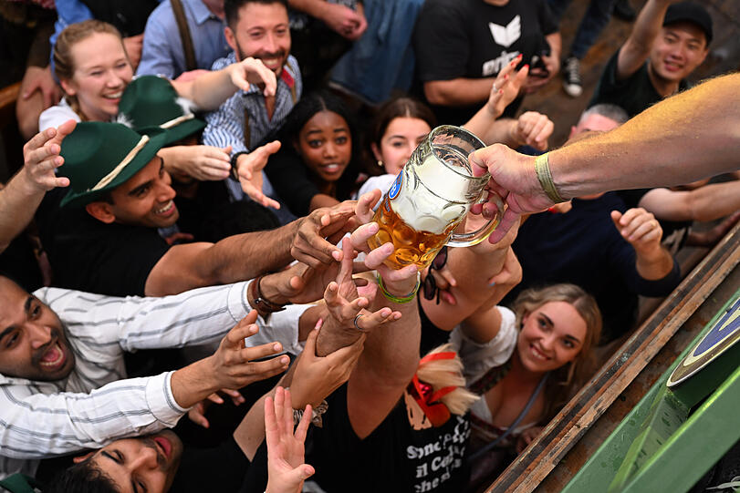 Gäste kämpfen im Hofbräuzelt um eines der ersten Biere, das von der Bühne herabgereicht wird.