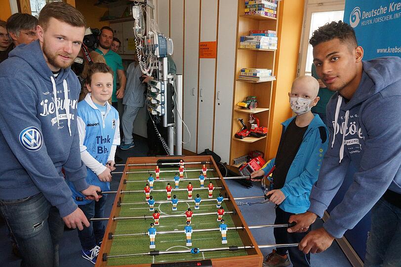 Stephan Hain und Rubin Okotie spielen eine Runde Kicker mit Thomas (12) und Jannik (9)