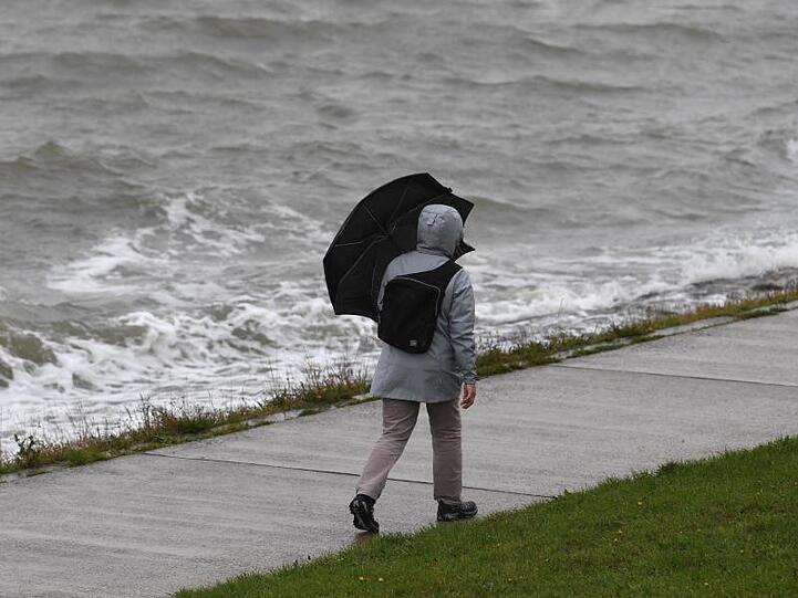Ein Frau geht bei Regen und Wind spazieren. Tief "Mortimer" zieht von den Britischen Inseln über die Nordsee und weiter zur Ostsee.