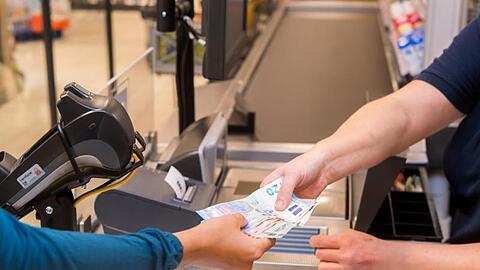 In einem Supermarkt hebt eine Kundin beim Bezahlen auch gleich Bargeld ab.