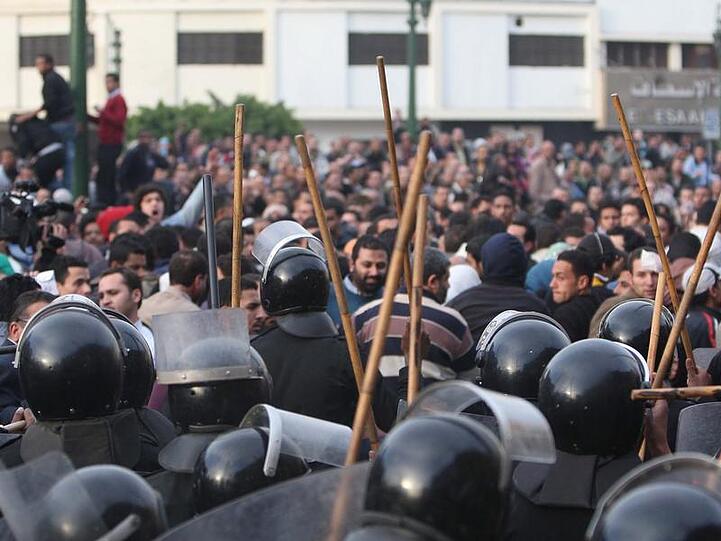 Die Polizisten gehen mit Schlagstöcken auf Demonstranten los.