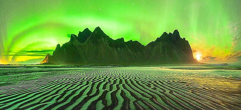 Die Nordlichter über dem isländischen Berg Vestrahorn ("Batman Berg"). Der Sand reflektiert das Licht.