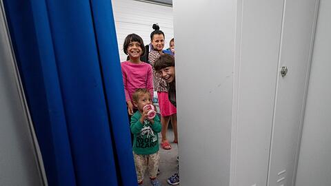 Kinder mit ihren Eltern schauen aus einem Wohnabteil der Erstanlaufstelle in Mammendorf.