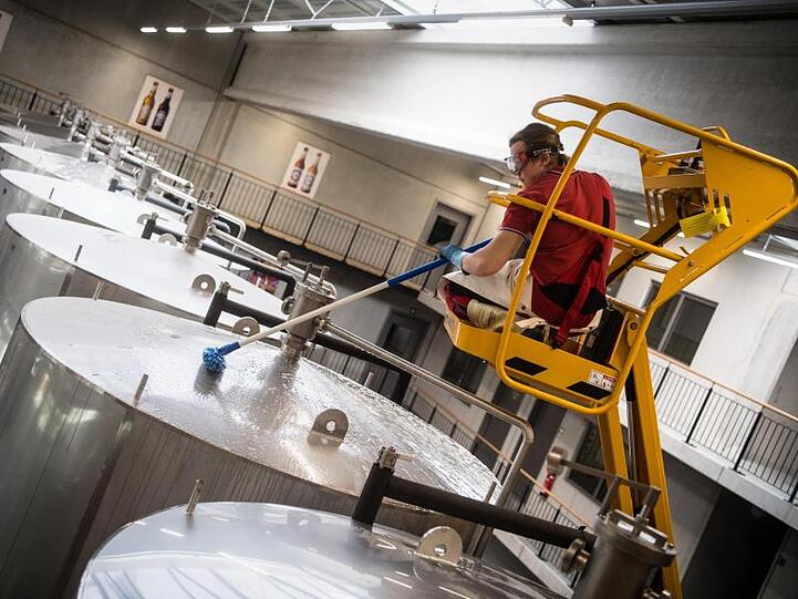 Ein Brauergeselle reinigt im Sudhaus einer Brauerei die Lagertanks. Foto: Matthias Balk/Archivbild