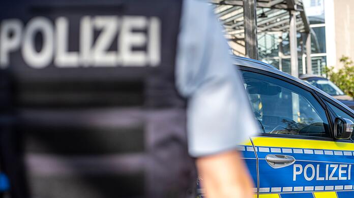 Ein Polizist steht vor einem Streifenwagen.