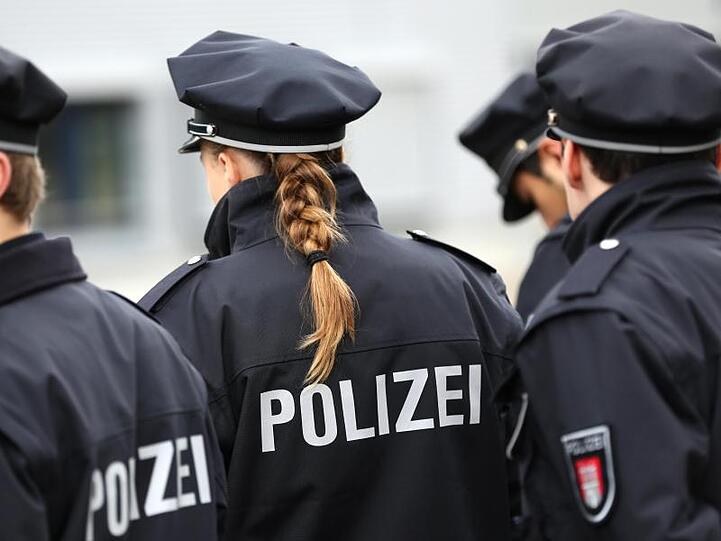 Die Aufschrift Polizei steht auf dem Rücken von Polizeiuniformen, die mehrere Polizisten tragen. Foto: Christian Charisius/Archiv