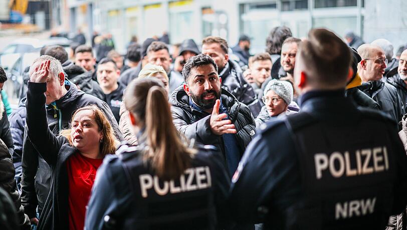 Aufgebrachte Kunden diskutieren vor der Sparkassenfiliale in Buer mit Polizeibeamten nach der R&auml;umung des Vorraums der Filiale.