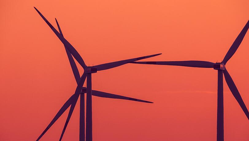 Die Rotoren von Windkraftanlagen drehen sich nach Sonnenuntergang.