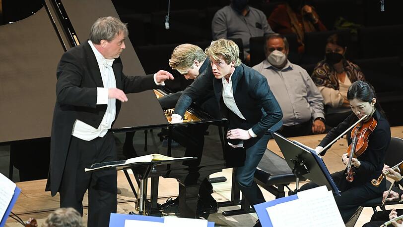 Lucas und Arthur Jussen zupfen an den Saiten im Klavierkorpus, John Storgaards dirigiert die Münchner Philharmoniker.