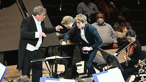 Lucas und Arthur Jussen zupfen an den Saiten im Klavierkorpus, John Storgaards dirigiert die Münchner Philharmoniker.