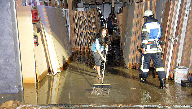 Nach einem Unwetter schiebt eine Frau in Schorndorf Wasser aus einer überfluteten Garage. Nach einem Unwetter schiebt eine Frau in Schorndorf Wasser aus einer überfluteten Garage.