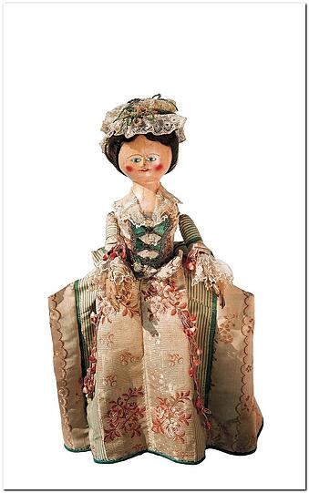 Diese Holzpuppe aus England ist deutlich älter als die meisten Exponate. Die Puppe wurde in London bei Sotheby's ersteigert, sie zeigt die feine Dame von Welt. Das Puppenkleid ist aus Brokat-Stoffbahnen, das Mieder aus grüner Seide. Adrett ist auch die Spitzenhaube.