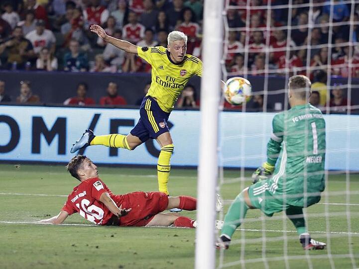 Arsenal-Spieler Mesut Özil (M/oben) kommt gegen Jonas Kehl (l) zum Schuss auf das Tor von Manuel Neuer.