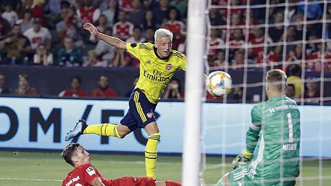 Arsenal-Spieler Mesut Özil (M/oben) kommt gegen Jonas Kehl (l) zum Schuss auf das Tor von Manuel Neuer.