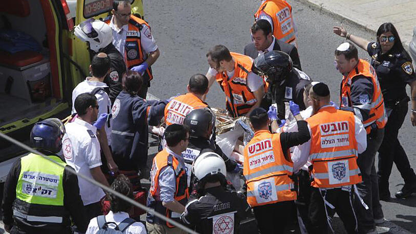 Rettungskräfte behandeln in Jerusalem nach einem Messerangriff eine Frau.