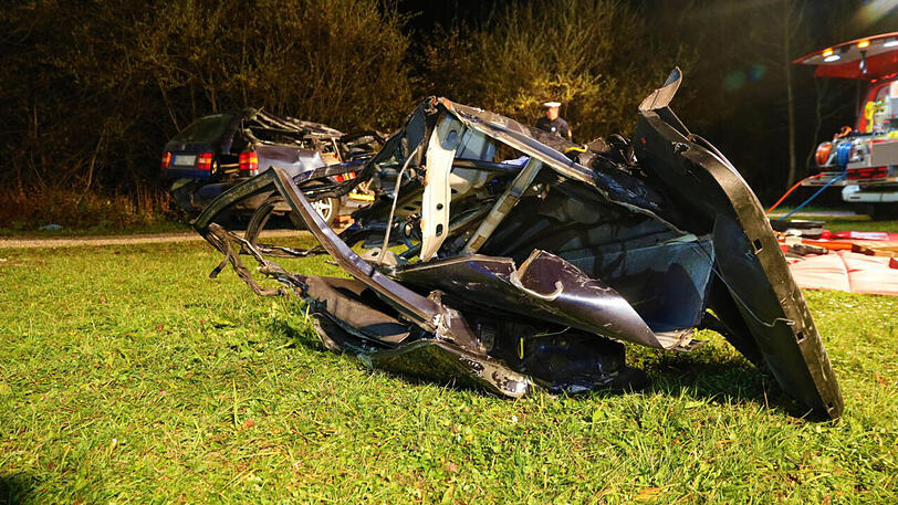 Autoteile liegen nach dem Verkehrsunfall auf einer Wiese.