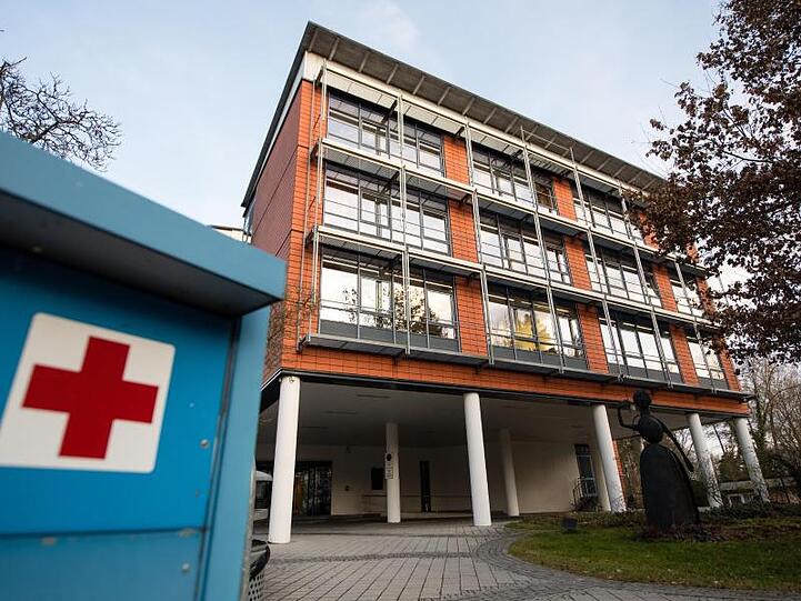 Ein rotes Kreuz ist auf einem Hinweisschild vor dem Gebäude der Kreisklinik Trostberg zu sehen. Foto: Matthias Balk/dpa
