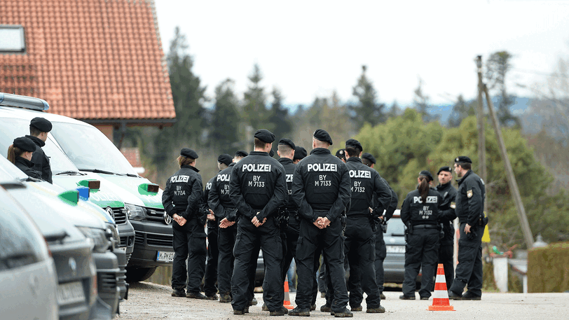 Polizisten stehen in der Zufahrtstraße zu dem Haus im Königsdorfer Ortsteil Höfen im Landkreis Bad Tölz-Wolfratshausen, in dem im Februar 2017 zwei Senioren getötet und die Hausbesitzerin schwer verletzt wurden. Sie wurden Opfer von Einbrechern. Diese müssen sich von Mittwoch an wegen Mordes vor Gericht verantworten.